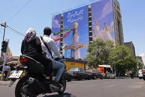 Penunggang motosikal melintasi sepanduk gergasi memaparkan peluru berpandu Iran dan pedang milik Imam Ali, imam pertama penganut Syiah, di Dataran Vanak, Teheran pada 10 Jun 2026. Kementerian Luar Iran berkata Amerika Syarikat telah menjejaskan usaha diplomatik antarabangsa yang sedang berlangsung untuk menamatkan perang selepas Washington melancarkan lagi serangan ke atas sasaran di selatan Iran.