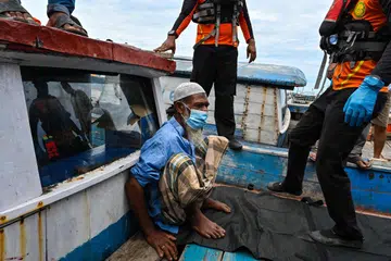 Seorang pelarian Rohingya yang sakit di atas sebuah bot di Labuhan Haji, wilayah Aceh Selatan, dibantu oleh kakitangan agensi mencari dan menyelamat Indonesia pada 20 Oktober. 