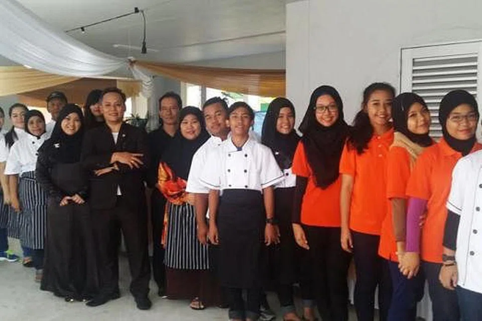 BAK SEBUAH KELUARGA BESAR: Pemilik Fizita Group Pte Ltd, Encik Raffiz Abdul Rahman (berpeluk tubuh), bersama isteri, Cik Masita Ismail (berjubah hitam), bergambar bersama kakitangan syarikat. - Foto FIZITA GROUP PTE LTD 