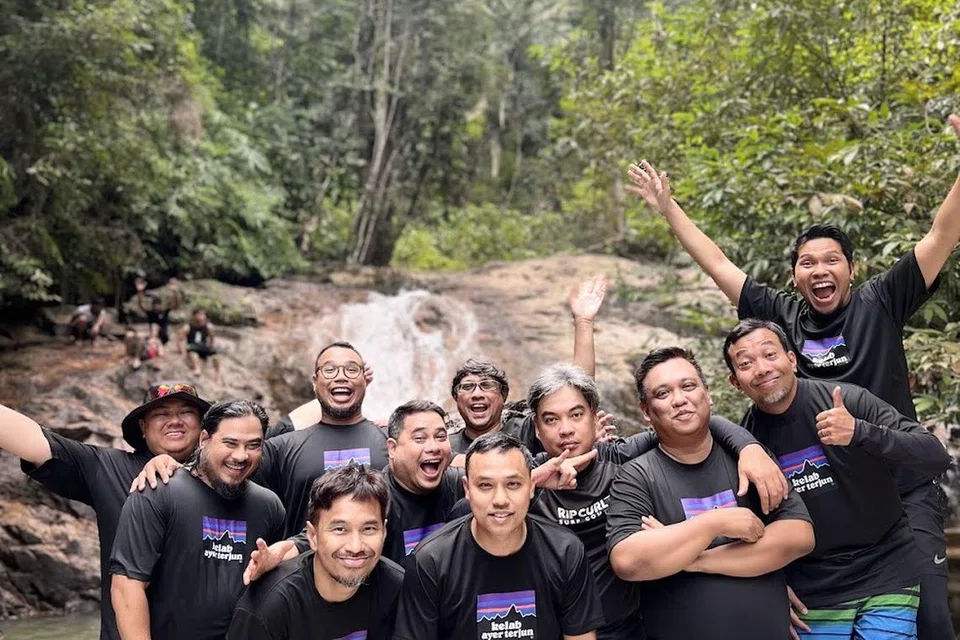 Encik Mohammad Ridzuan Abdul Aziz (paling kanan, angkat tangan) dan Encik Mohamad Firdaus Hasbullah (paling kiri, bertopi)) berkunjung ke Air Terjun Takah Pengkoi di Bekok, Johor, pada Julai 2025 bersama anggota Kelab Ayer Terjun lain.