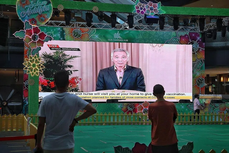 SITUASI TERKINI PANDEMIK: Orang awam menonton ucapan Perdana Menteri Lee Hsien Loong yang ditayang secara live di Our Tampines Hub semalam. - Foto BH oleh KEVIN LIM