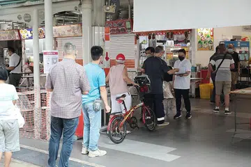 LANGKAH DIPERKETAT: Pegawai sekitaran dan Majlis Bandaran mengawasi laluan masuk SafeEntry di Pasar dan Pusat Penjaja Geylang Bahru semalam. - Foto ZAOBAO 
