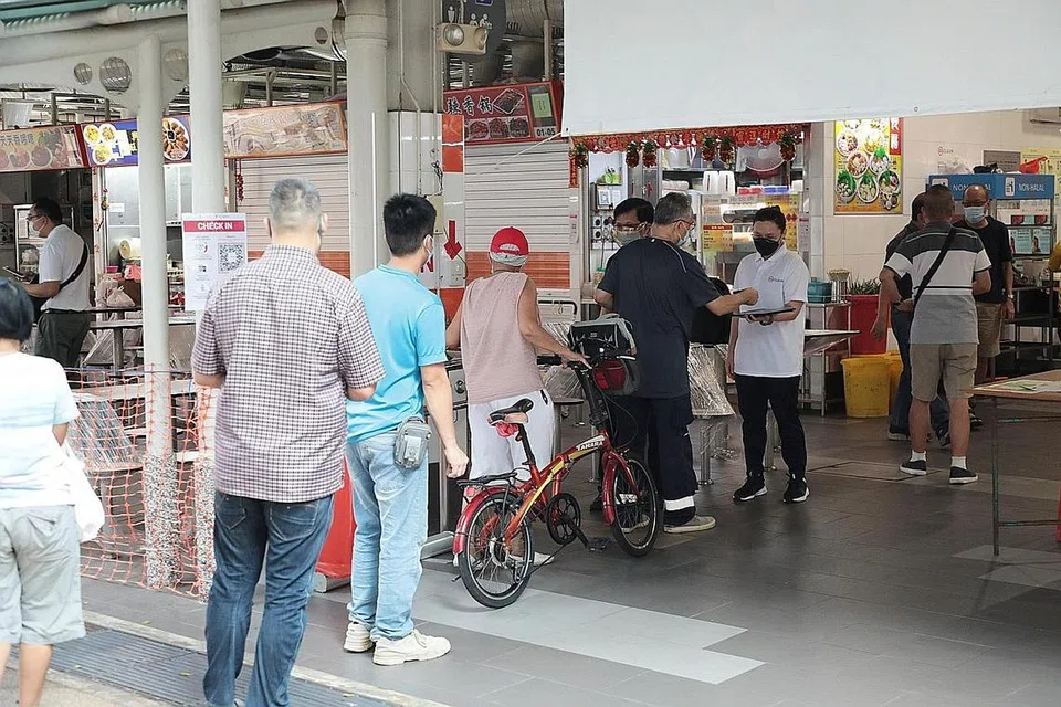 LANGKAH DIPERKETAT: Pegawai sekitaran dan Majlis Bandaran mengawasi laluan masuk SafeEntry di Pasar dan Pusat Penjaja Geylang Bahru semalam. - Foto ZAOBAO 