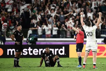 ALL BLACKS TEWAS: Pemain 'back row' England, Mark Wilson, (No. 20) meraikan kemenangan pasukannya sementara pemain 'fly-half' New Zealand, Richie Mo'unga (kiri) dan pemain 'wing' Sevu Reece kelihatan kecewa selepas ditewaskan dalam perlawanan separuh akhir Piala Dunia Ragbi di Stadium Antarabangsa Yokohama semalam. -Foto AFP. 