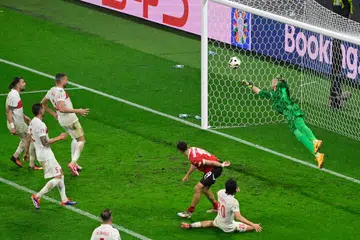 Penjaga gawang Turkey, Mert Gunok (jersi hijau), menyelamatkan tandukan Christoph Baumgartner (jersi merah) pada minit ke-94 untuk memastikan Turkey memenangi perlawanan 2-1 ke atas Austria. 