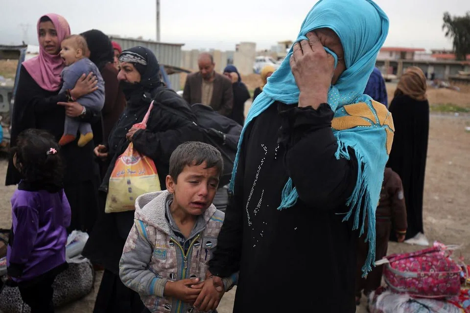 MENYAYAT HATI: Seorang wanita bersama anaknya dalam kepiluan semasa disambut saudara mara pada 11 April lalu, setelah suami dan anak-anak lelakinya mati dibunuh oleh kumpulan pengganas Negara Islam (IS), sewaktu mereka cuba melarikan diri dari kediaman mereka di kejiranan Sekak di barat Mosul. Keupayaan wanita itu dan anaknya untuk keluar dari kawasan yang ditadbir IS itu diselia oleh pasukan perangi terorisme Iraq (CTS), yang berusaha menawan semula bandar itu daripada IS. - Foto AFP