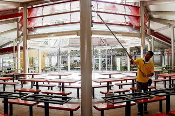 NAFAS BARU: Seorang pekerja mengecat tiang di Pusat Makanan Adam Road bagi memberi nafas baru kepada pusat makanan itu. - Foto-foto ZAINAL YAHYA