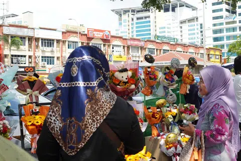 PENUHI CITA RASA PELANGGAN: Cik Qaseh Maria (tudung biru) melayan seorang pelanggan yang ingin membeli jambangan bunga untuk dihadiahkan semasa hadiri majlis konvokesyen.               