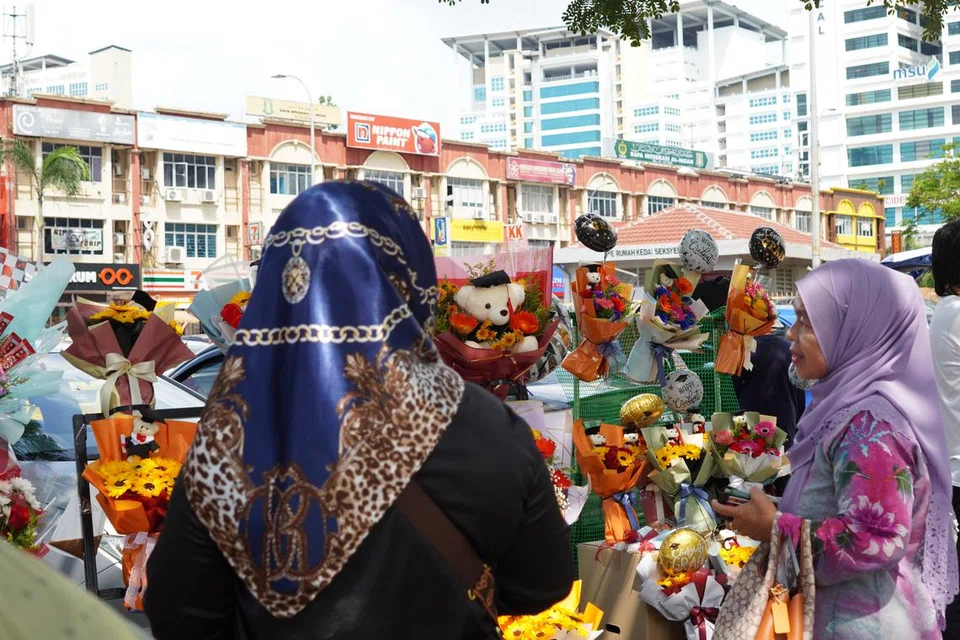 PENUHI CITA RASA PELANGGAN: Cik Qaseh Maria (tudung biru) melayan seorang pelanggan yang ingin membeli jambangan bunga untuk dihadiahkan semasa hadiri majlis konvokesyen.               