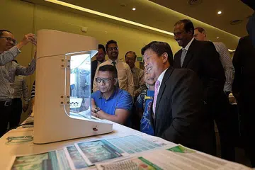 MANFAAT TEKNOLOGI: Encik Saifuddin Hashim (duduk, kiri), 31 tahun, memperkenal Encik Chee Meng (duduk, kanan) dan Aidan Toh (tengah) 6 tahun kepada Bio X, pencetak bio yang boleh mencetak sel. NTUC, e2i dan CIEU mengumumkan pelancaran Masyarakat Latihan Sains Bioperubatan (BMTC) bagi menyediakan latihan dan kepimpinan bagi para pekerja. - Foto BH oleh ALPHONSUS CHERN
