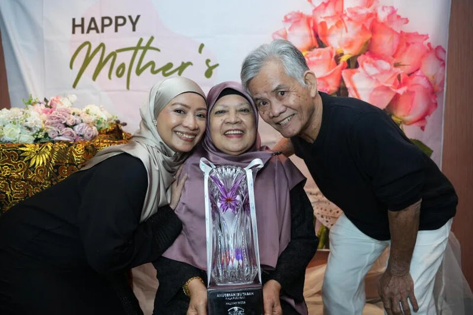Pemenang Anugerah Ibu Tabah Persatuan Ain 2024, Cik Siti Asmaniah Nasiruddin (tengah) bersama anaknya, Cik Zuhaidah Kassim (kiri), dan suami, Encik Kassim Jusi, semasa sambutan Hari Ibu Persatuan Ain di Hotel Concorde pada 25 Mei.
