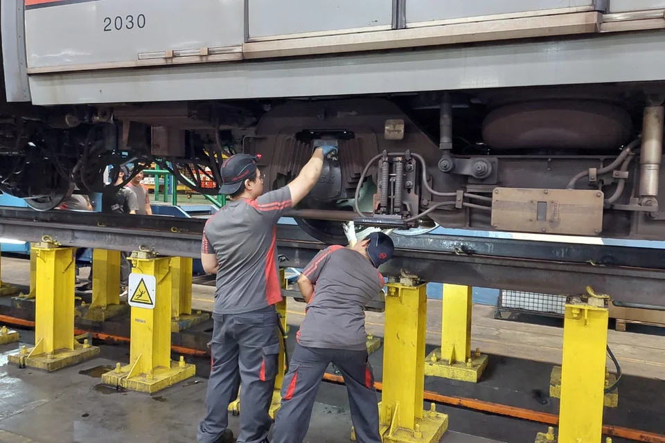Petugas SMRT melakukan pemeriksaan pada kotak gandar kereta api.