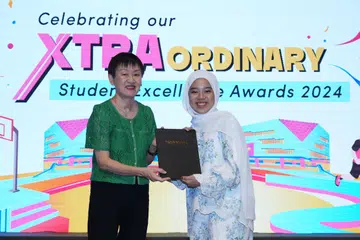 Cik Camelia Sephiana Nor Azmi (kanan), menerima Anugerah Pujian Khas: Khidmat Masyarakat daripada Politeknik Ngee Ann (NP) yang meraikan pencapaian ke-20 Anugerah Kecemerlangan Pelajar (SEA) pada 18 Julai, disampaikan oleh Pengarah Kanan Pelajar NP, Cik Tang-Lim Guek Im.