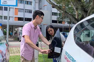 TEMPAT MENGECAS: Encik Ng Xiang Long, jurutera kanan dari Pusat Kenderaan Elektrik Nasional, Pembangunan Teknologi dan Industri, LTA, menunjukkan hos The BM Show Irma Kamarudin, cara kereta elektrik dicas. Encik Ng turut berkata sebanyak 60,000 tempat pengecas EV, termasuk 40,000 di tempat meletak kereta awam, akan disediakan menjelang 2030. - Foto BM oleh NUR HUMAIRA SAJAT