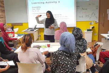 REZEKI TAMBAH KEMAHIRAN: Cik Juriah (berdiri), yang kini seorang jurulatih bagi program 'Wanita Kembali Bekerja' di Mendaki Sense, sering mempertingkat kemahiran dan memperbaiki diri sendiri agar memperolehi banyak ilmu untuk dikongsi bersama para pelatih. - Foto ihsan JURIAH JAHAYA