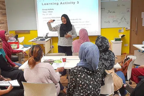 REZEKI TAMBAH KEMAHIRAN: Cik Juriah (berdiri), yang kini seorang jurulatih bagi program 'Wanita Kembali Bekerja' di Mendaki Sense, sering mempertingkat kemahiran dan memperbaiki diri sendiri agar memperolehi banyak ilmu untuk dikongsi bersama para pelatih. - Foto ihsan JURIAH JAHAYA