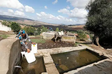 TUGAS WANITA KUMPUL AIR: Seorang wanita mengisi beberapa bekas air dari sebuah telaga di Oued al-Berber, Tunisia, sebelum dibawa pulang menggunakan keldai sebagai satu bentuk pengangkutan. - Foto REUTERS