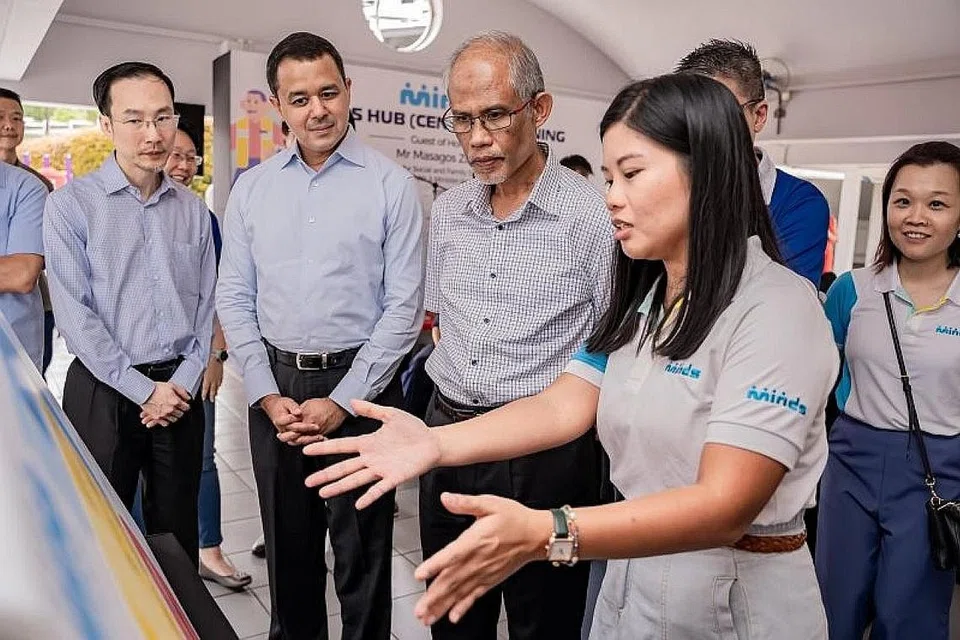LAWATAN KE HAB BARU: Encik Masagos (dua dari kanan) diberi taklimat mengenai program sokongan penjaga yang ditawarkan Minds oleh pengurus program perkembangan dan pejabat sokongan Minds, Cik Julia Ng (kanan), semasa lawatan di Minds Hub (Central) yang baru dilancarkan di 2 Queens Road. Hab itu berfungsi sebagai pusat sehenti fizikal yang menawarkan pelbagai perkhidmatan untuk golongan kurang daya intelek (PWID). Bersama dalam gambar (dari kiri) ialah pengerusi Minds, Encik Augustin Lee dan Timbalan Speaker Parlimen yang juga AP GRC Holland-Bukit Timah, Encik Christopher de Souza. - Foto BH oleh NUR DIYANA TAHA