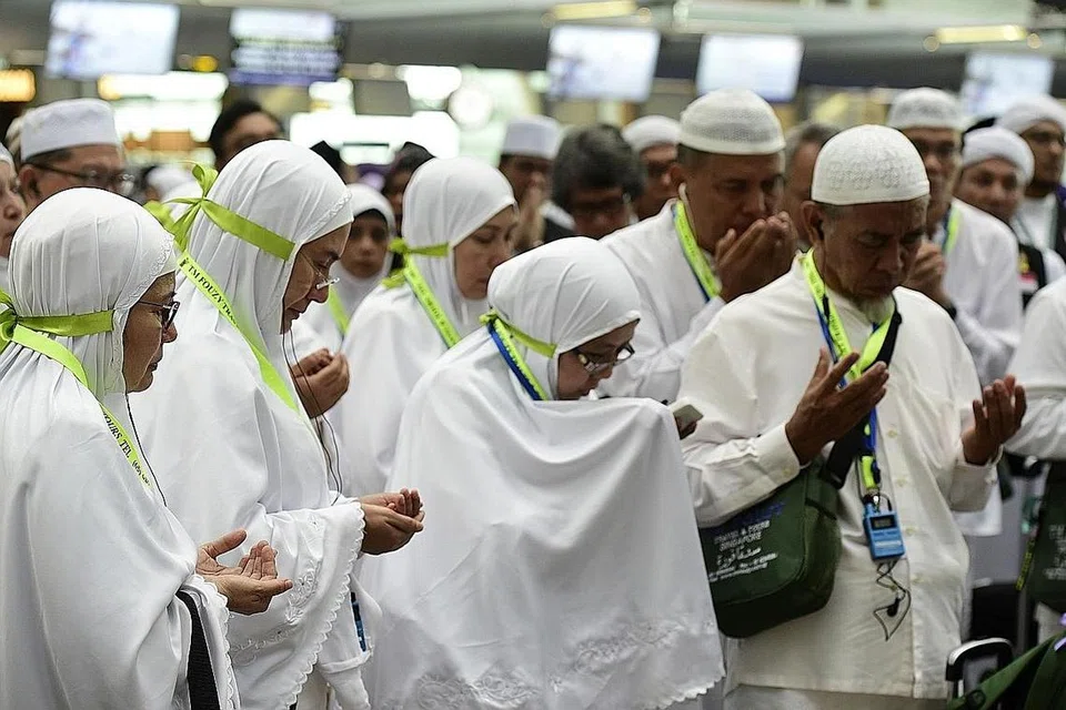 MEMANJAT DOA: Sekumpulan jemaah haji setempat berkumpul mengaminkan doa yang dibacakan sebelum memasuki Dewan Berlepas Terminal 3 dengan menaiki pesawat Saudi Airlines. - Foto BH oleh DIOS VINCOY JR