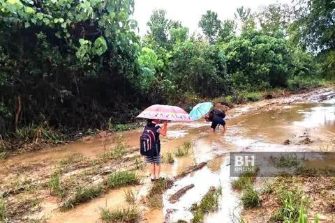RUTIN PERIT: Darren Dinis dan adiknya Sheryl terpaksa meredah jalan berlumpur hingga kaki mereka berkudis untuk ke sekolah. Keperitan itu perkara rutin bagi penduduk Kampung Tampakahu, 28 km dari Pitas di utara Kota Kinabalu, kerana itu saja jalan yang menghubungkan kampung mereka.