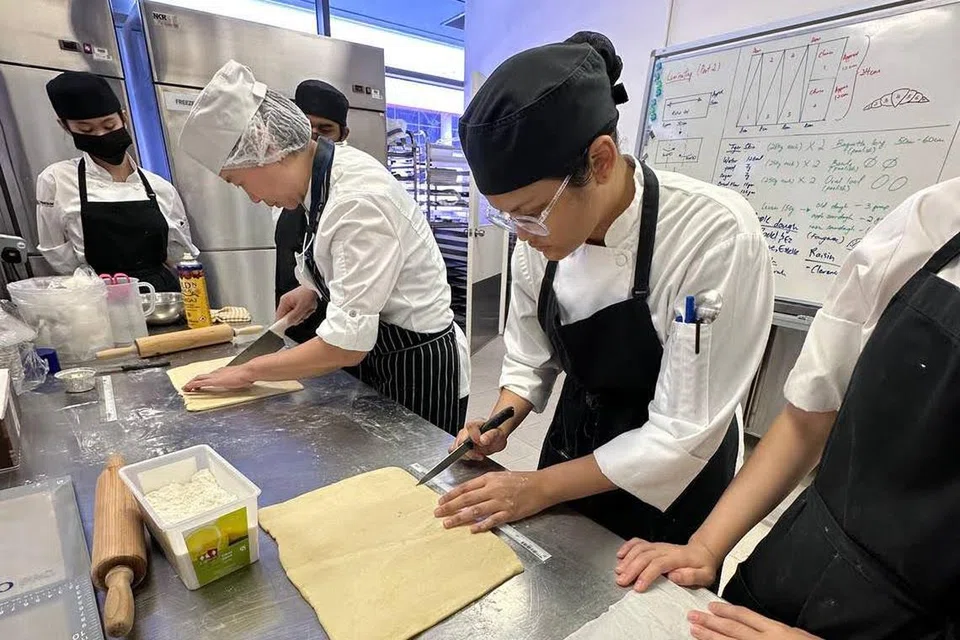 Cik Fatin Aishah Hirwanis yang lulus dengan Diploma dalam Perniagaan Makanan dan Minuman dengan Merit, semasa sesi latihan menyediakan pastri di sekolah. 