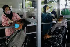 Pekerja kesihatan menjalankan ujian Covid-19 ke atas penumpang di sebuah stesen kereta api pada 13 Januari 2022, di tengah-tengah penularan varian Omicron di Jakarta.
