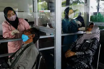 Pekerja kesihatan menjalankan ujian Covid-19 ke atas penumpang di sebuah stesen kereta api pada 13 Januari 2022, di tengah-tengah penularan varian Omicron di Jakarta.