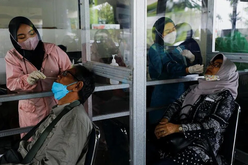 Pekerja kesihatan menjalankan ujian Covid-19 ke atas penumpang di sebuah stesen kereta api pada 13 Januari 2022, di tengah-tengah penularan varian Omicron di Jakarta.