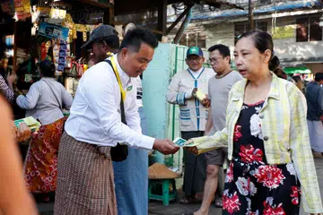 Than Naing Soe (kiri), calon Parti Demokratik Kebangsaan Shan (SNDP) yang juga dikenali sebagai Parti Harimau Putih, mengedarkan risalah kempen pada hari terakhir tempoh berkempen di Yangon, Myanmar, pada 26 Disember 2025. Pemerintah tentera Myanmar melalui Majlis Pentadbiran Negara (SAC) merancang mengadakan pilihan raya nasional pertama sejak rampasan kuasa Februari 2021 menerusi pilihan raya umum berperingkat, dengan fasa pertama dijadualkan pada 28 Disember 2025 dan fasa kedua pada 11 Januari 2026. Lebih 50 parti politik telah mendaftar untuk menyertai pilihan raya itu, menurut Suruhanjaya Pilihan Raya Kesatuan (UEC), manakala parti pembangkang pro-demokrasi utama, Liga Kebangsaan untuk Demokrasi (NLD), telah dibubarkan sejak Mac 2023. 