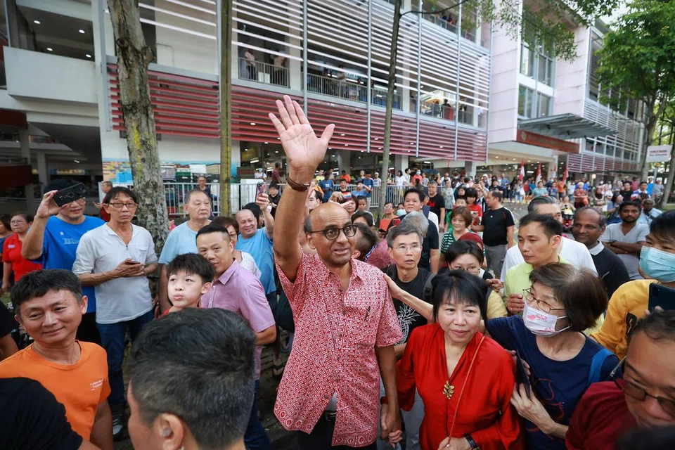 DIKELILINGI PENYOKONG: Bakal Presiden, Encik Tharman Shanmugaratnam, ditemani isterinya, Cik Jane Ittogi, melambai dan mengucapkan terima kasih kepada penyokongnya sedang beliau meninggalkan Pusat Penjaja Taman Jurong pada Sabtu.