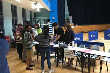 PENGINAPAN SEMENTARA: Beberapa pekerja Malaysia mendaftarkan diri untuk menginap di Dewan Sukan Jurong East pada malam Rabu (18 Mac).