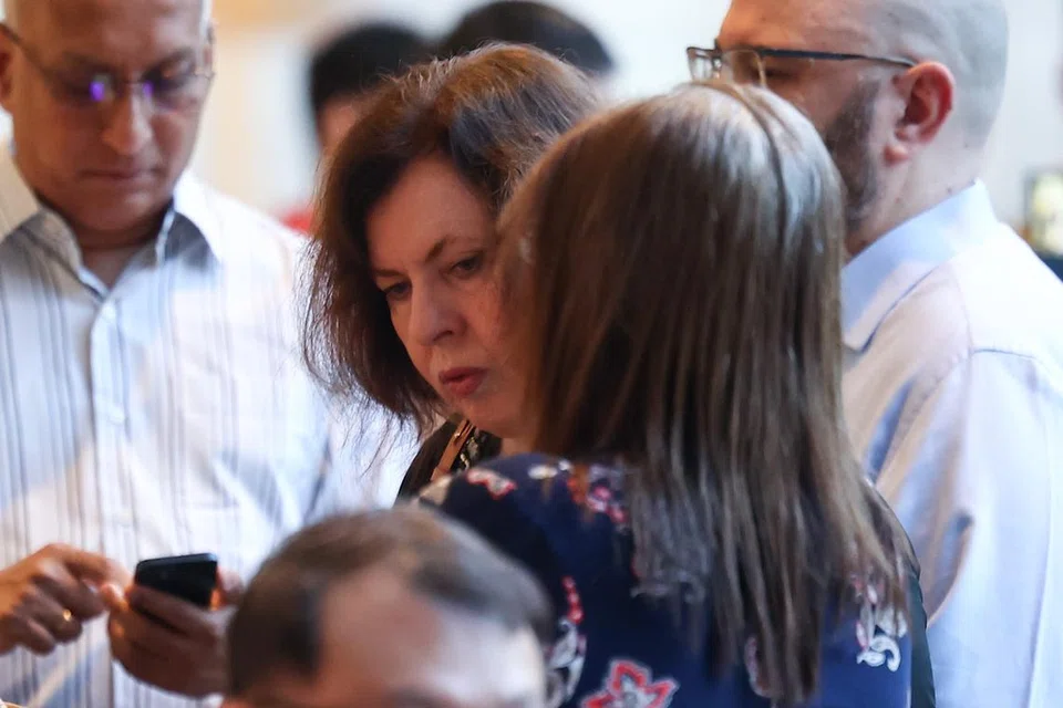 Isteri Iswaran, Cik Kay Mary Taylor, dirakam sedang beratur untuk mendapatkan tiket bagi menghadiri perbicaraan.