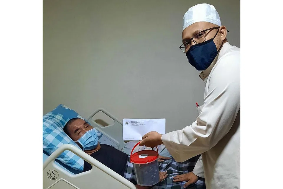 BANTUAN RAHMAH: Ustaz Achmed Fahdly Mohd Kamsari (kanan) daripada Pergeraq menghulurkan sumbangan Ramadan kepada ahli Kumpulan Orang Cacat Muslim Singapura (KCMS) pada 2022. - Foto PERGERAQ 