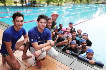 LATIHAN BERSAMA JUARA: 12 belia dari pertubuhan Care Singapura, berpeluang mengikuti latihan yang dikendalikan juara Olimpik negara, Schooling (dua dari kiri) dan jurulatih dari Swim Schooling di kolam renang Kelab Temasek semalam. - Foto BH oleh KELVIN CHNG