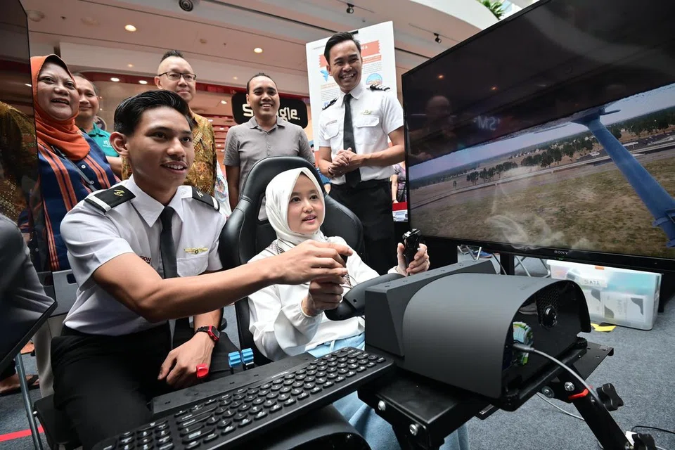 Menteri Negara (Penerangan dan Pembangunan Digital merangkap Kesihatan), Cik Rahayu Mahzam (depan, kanan), sedang mencuba salah satu kegiatan yang disediakan semasa acara ‘Raikan Ilmu@Heartlands’ (Jurong) di Jurong Point. Turut hadir di acara itu ialah Anggota Parlimen (AP) GRC Jurong, Dr Tan Wu Meng (belakang, tiga dari kanan); dan AP GRC Chua Chu Kang, Encik Zhulkarnain Abdul Rahim (belakang, dua dari kanan).