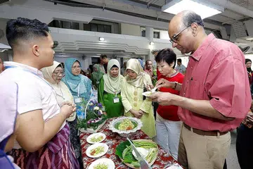 BULAN BAHASA DI KEJIRANAN: (Dari kanan) Encik Tharman Shanmugaratnam, Cik Grace Fu dan Cik Rahayu Mahzam merasa hidangan hasil tangan Encik Azfar Maswan (kiri), 'Nasi Ulam Nyona', yang menang dalam pertandingan memasak Resipi Warisan pada acara Bulan Bahasa 2019 @ Jurong. - Foto PERSATUAN RAKYAT