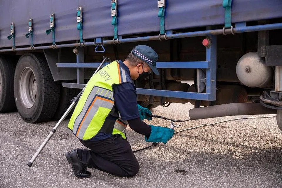 Seorang pegawai penguatkuasa melakukan ujian pelepasan asap pada kenderaan komersial berat.