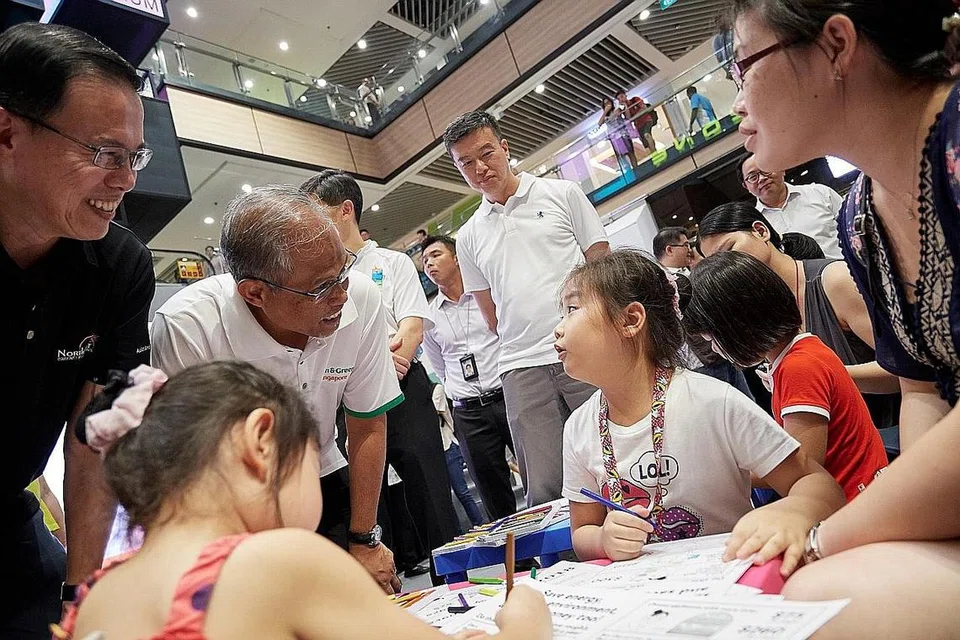 BINCANG CARA JIMAT TENAGA: Encik Masagos Zulkifli Masagos Mohamad (berkemeja-T putih) bermesra dengan Charlene Ng, tujuh tahun, yang menyertai kegiatan mewarna, sempena pelancaran 'Cabaran Jimat Tenaga', sambil diperhatikan oleh Mayor CDC North West Teo Ho Pin (kiri). - Foto BM oleh LIN ZHAOWEI