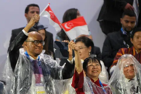 Presiden Tharman Shanmugaratnam dan isteri, Puan Jane Ittogi mengibarkan bendera Singapura ketika pasukan Olimpik Singapura muncul di skrin di Trocadero semasa upacara pembukaan Sukan Olimpik Paris 2024.