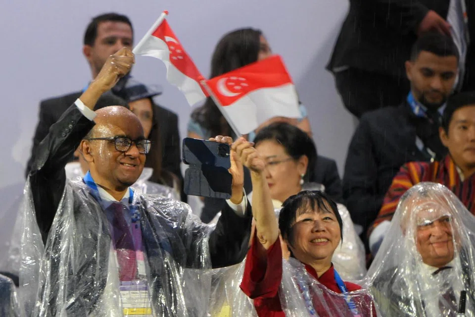 Presiden Tharman Shanmugaratnam dan isteri, Puan Jane Ittogi mengibarkan bendera Singapura ketika pasukan Olimpik Singapura muncul di skrin di Trocadero semasa upacara pembukaan Sukan Olimpik Paris 2024.