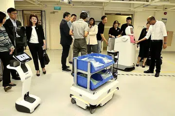 DEMONSTRASI SEPADU PENGGUNAAN ROBOT AUTONOMI: Dr Janil Puthucheary (kanan) mengadakan kunjungan tertutup di Hospital Besar Changi untuk menyaksikan demonstrasi menyepadukan penggunaan robot autonomi melalui rangka kerja 'middleware', lapisan perisian yang membolehkan robot berbeza bercakap sesama sendiri. - Foto ZAOBAO