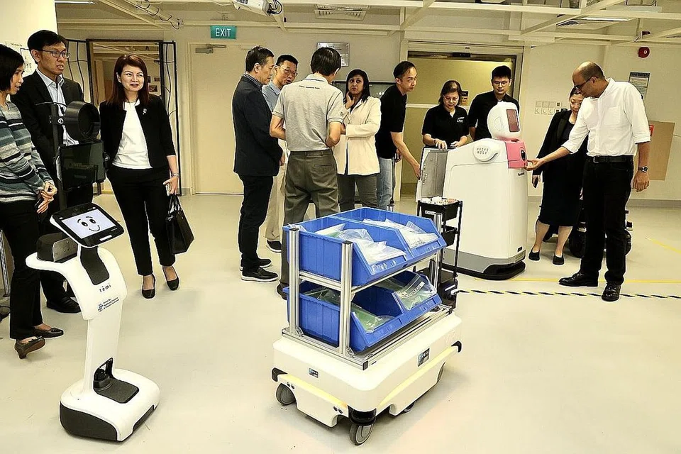 DEMONSTRASI SEPADU PENGGUNAAN ROBOT AUTONOMI: Dr Janil Puthucheary (kanan) mengadakan kunjungan tertutup di Hospital Besar Changi untuk menyaksikan demonstrasi menyepadukan penggunaan robot autonomi melalui rangka kerja 'middleware', lapisan perisian yang membolehkan robot berbeza bercakap sesama sendiri. - Foto ZAOBAO