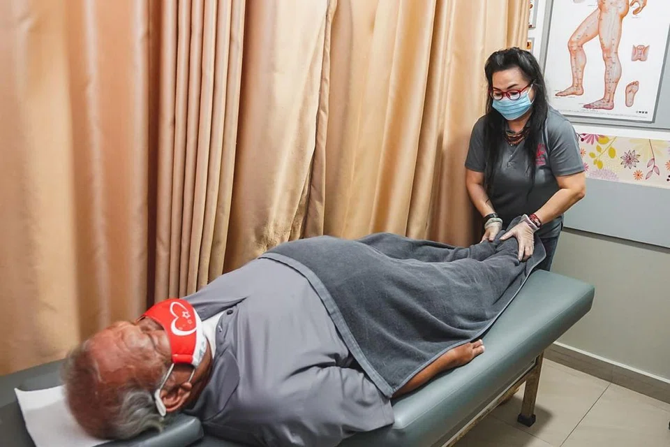 RAWAT KAKI: Encik Ahmad Ibrahim melakukan terapi urut Tuina di kakinya ketika mengunjungi Perubatan Institusi Sian Chay di Marsiling Drive untuk rawatannya. 