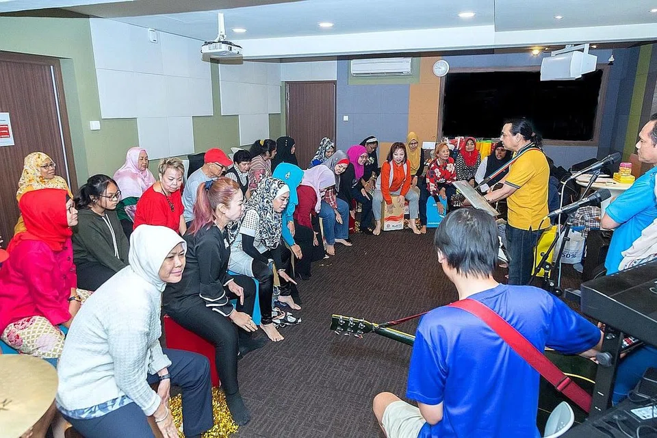 KELUARGA BESAR: Moliano Rasmadi (berbaju kuning) menikmati pengalaman membimbing warga emas dan anak muda yang ingin mendalami kemahiran memetik gitar dan memalu 'cajon'. - Foto BM oleh ZALEHA ABDUL KADER