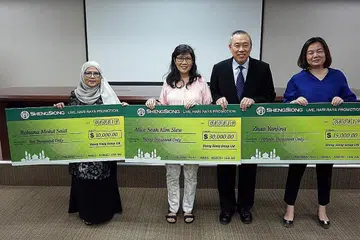 KEMENANGAN TAK DISANGKA: Cik Rohana (kiri) memenangi cabutan bertuah di tempat ketiga. Beliau bersama Cik Alice Seah Kim Siew (dua dari kiri), Ketua Pegawai Eksekutif Kumpulan Sheng Siong, Encik Lim Hock Chee (dua dari kanan) dan Cik Zhao YanJing (paling kanan). - Foto SHENG SEONG