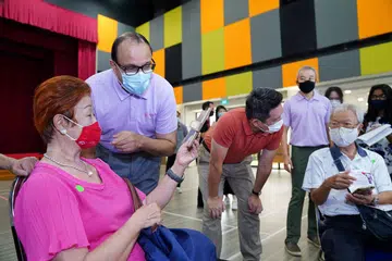 BELAJAR E-PEMBAYARAN: Seorang warga emas berkongsi dengan Encik Iswaran (dua dari kiri) kemahiran menggunakan wadah e-pembayaran yang dipelajarinya semasa satu sesi Perjalanan Pembelajaran e-Pembayaran di Kelab Masyarakat Teck Ghee semalam. - Foto MCI