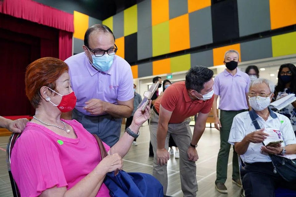 BELAJAR E-PEMBAYARAN: Seorang warga emas berkongsi dengan Encik Iswaran (dua dari kiri) kemahiran menggunakan wadah e-pembayaran yang dipelajarinya semasa satu sesi Perjalanan Pembelajaran e-Pembayaran di Kelab Masyarakat Teck Ghee semalam. - Foto MCI