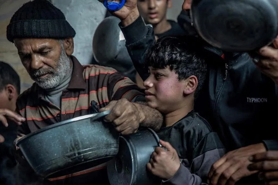 Rakyat Palestin di Gaza berkumpul untuk mengambil makanan bantuan yang disediakan di Beit Lahia, Gaza.