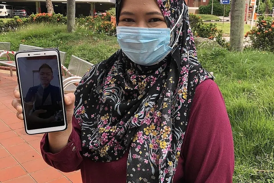 LEPASKAN RINDU: Cik Hanna sambil memegang telefon bimbitnya ketika menghubungi anak bongsunya Afiq, melalui panggilan video dari Singapura. - Foto ihsan HANNA