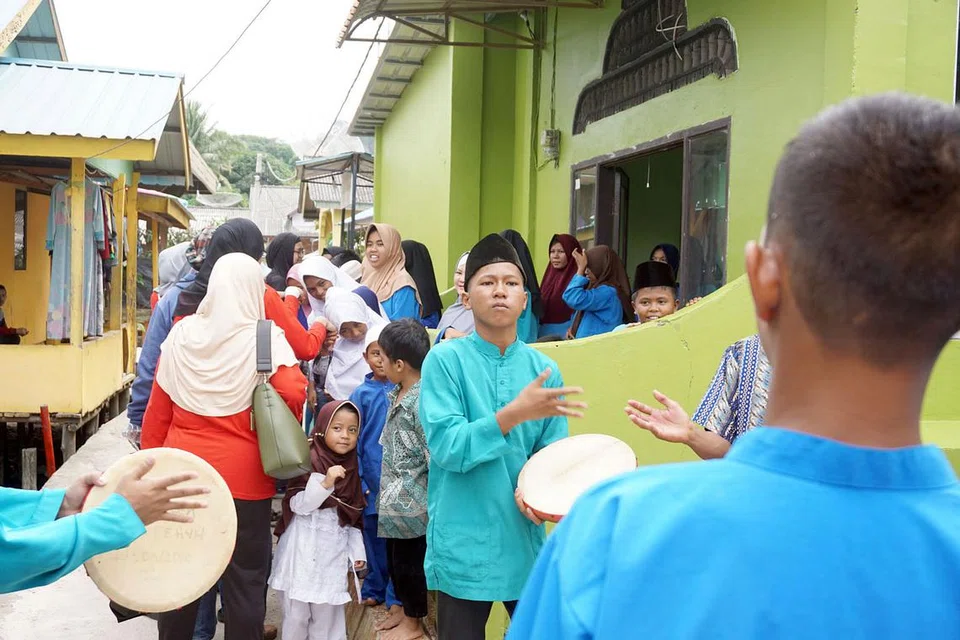 KEDATANGAN DIALU-ALUKAN: Kedatangan relawan Singapura disambut mesra dengan paluan kompang dan diiringi dengan nyanyian anak-anak panti asuhan tersebut.